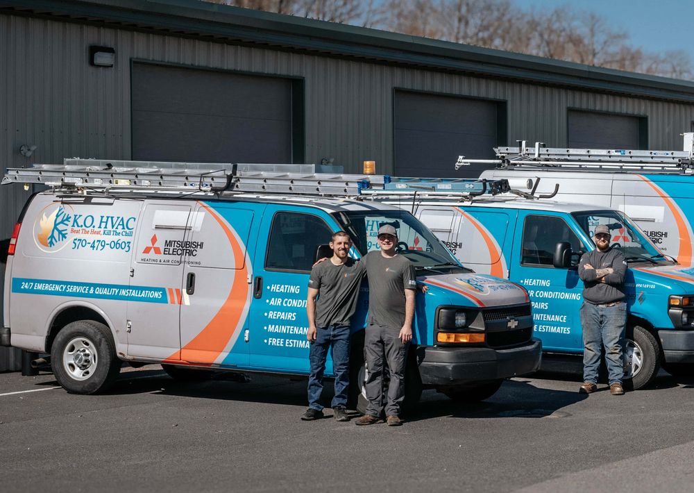The KO HVAC crew standing with their wrapped vans outside the Kingston shop