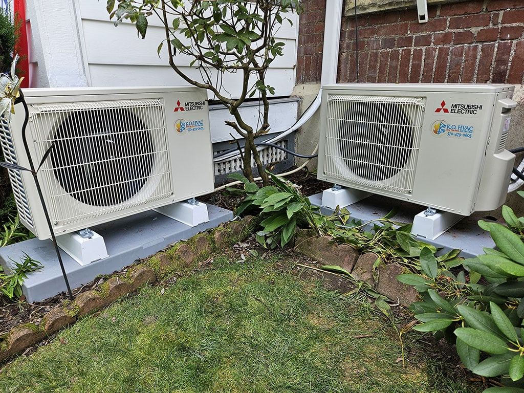 Two Mitsubishi air conditioners on concrete pads outside home in Kingston, PA.