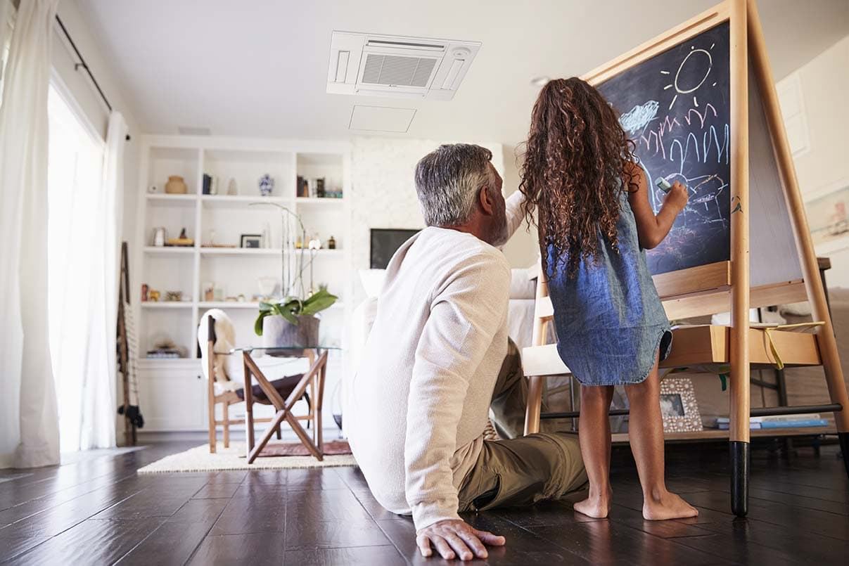 Grandfather sitting on the floor drawing on a blackboard with his young granddaughter, low angle