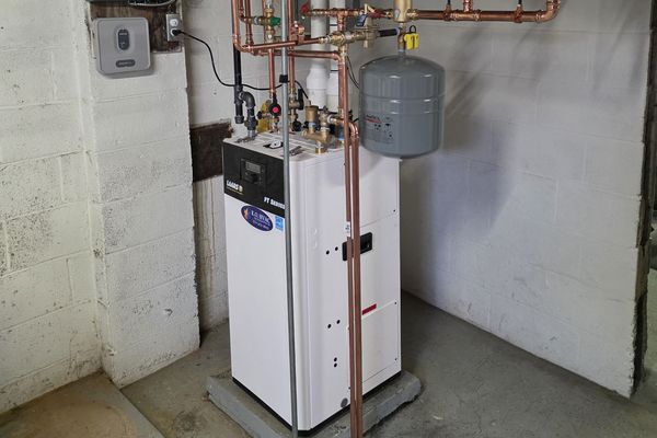A white boiler with a copper manifold and an expansion tank