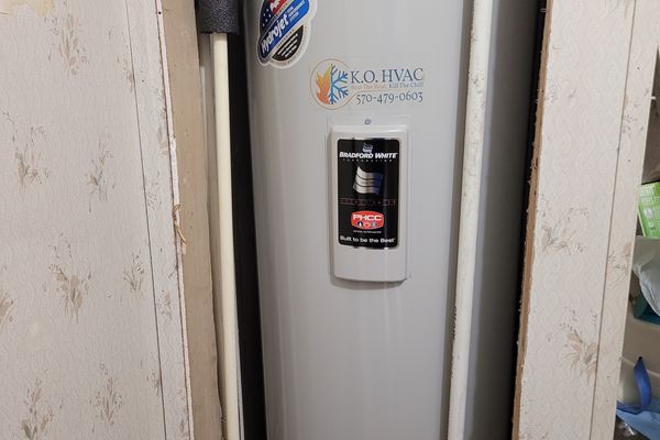 A water heater with a KO HVAC sticker in a utility closet