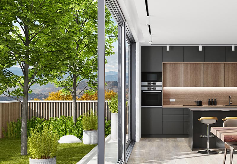 Country villa inteior with small garden. Modern black Italian style open concept kitchen with island table with three stools and lots of natural light.